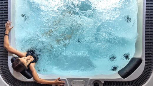 Vista-dall’alto-di-una-donna-che-si-rilassa-in-una piscina-idromassaggio-esterna-immersa-nellacqua-calda-in-un-momento-di-benessere-e-relax